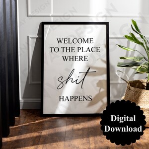 Puede incluir: Una impresión enmarcada con el texto "WELCOME TO THE PLACE WHERE shit HAPPENS" en un marco negro. Las palabras están en una fuente negra, de estilo manuscrito. Una insignia de descarga digital negra está en la esquina inferior derecha.