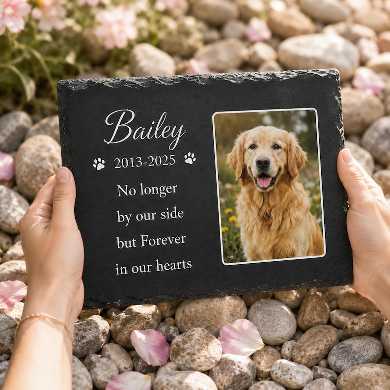 May include: A rectangular black slate memorial plaque featuring the name Bailey, the years 2013-2025, two paw prints, and the text No longer by our side but Forever in our hearts. A color photograph of a golden retriever is printed on the right side.
