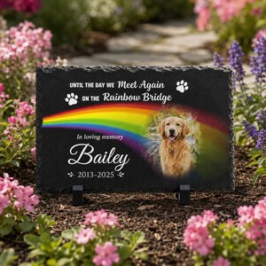 May include: A rectangular black slate memorial plaque featuring a colorful rainbow graphic, a portrait of a golden retriever, and the text: UNTIL THE DAY WE Meet Again ON THE Rainbow Bridge, In loving memory, Bailey, 2013-2025, with paw prints.