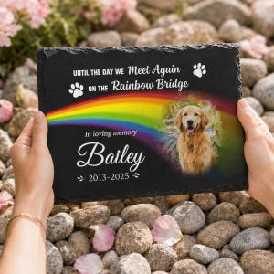 May include: A rectangular black slate memorial plaque featuring a printed rainbow graphic, a photograph of a golden retriever, and the text "UNTIL THE DAY WE Meet Again ON THE Rainbow Bridge", "In loving memory", "Bailey", and "2013-2025".