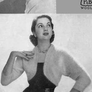 以下が含まれることがあります： 白いアンゴラボレロとそれに合わせた帽子をかぶった女性の白黒写真。画像の右側に「95-4° Cap and Bolero in Patons Fuzzy-Wuzzy Angora P&B WOOLS」というテキストが印刷されています。