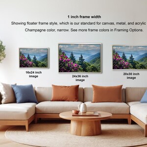 a living room with a large sectional sofa and a coffee table. There are four framed landscape photographs displayed on the wall, each with a different frame size ranging from 16" to 20" inches. The photographs depict various scenic outdoor landscapes, including mountains, forests, and meadows. The arrangement of the photographs and the overall layout of the living room create a cozy and inviting atmosphere.