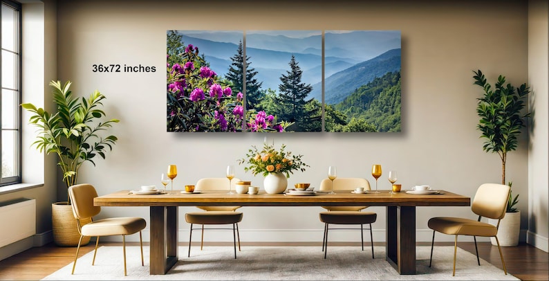 a large, three-panel landscape painting hanging on a wall above a wooden dining table with four chairs. The painting depicts a scenic mountain landscape with purple flowers in the foreground.