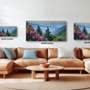 A living room with a large sectional sofa, a coffee table, and three framed landscape paintings hanging on the wall.