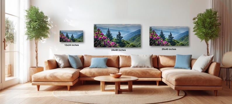 A living room with a large sectional sofa, a coffee table, and three framed landscape paintings hanging on the wall.