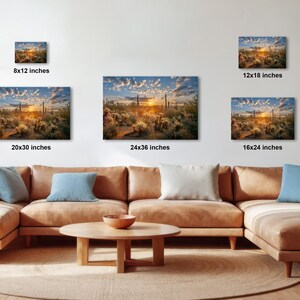 a large, brown sectional sofa with multiple pillows, a wooden coffee table, and a potted plant in the background. The sofa is positioned in front of a wall with three framed landscape photographs of varying sizes, each depicting a different scene.
