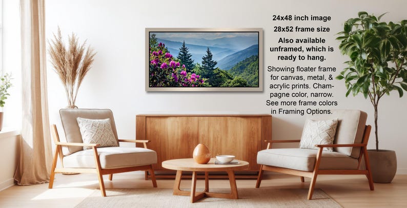 a living room with a wooden coffee table, two white armchairs, and a framed landscape photograph hanging on the wall.