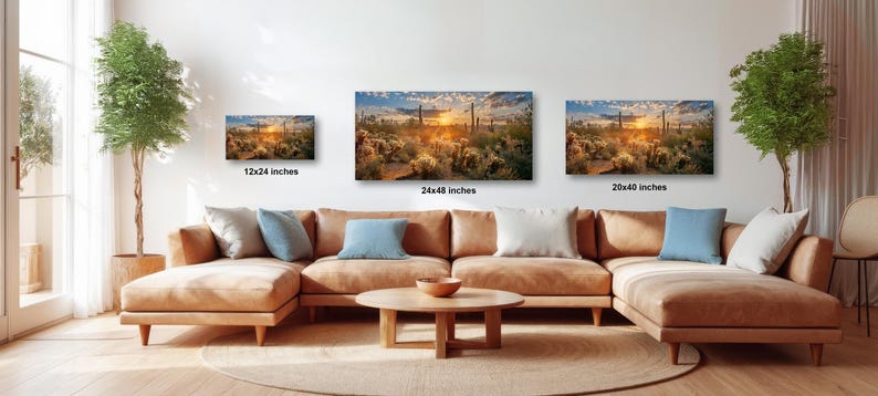 a living room with a large sectional sofa, a coffee table, and three framed landscape paintings hanging on the wall above the sofa.