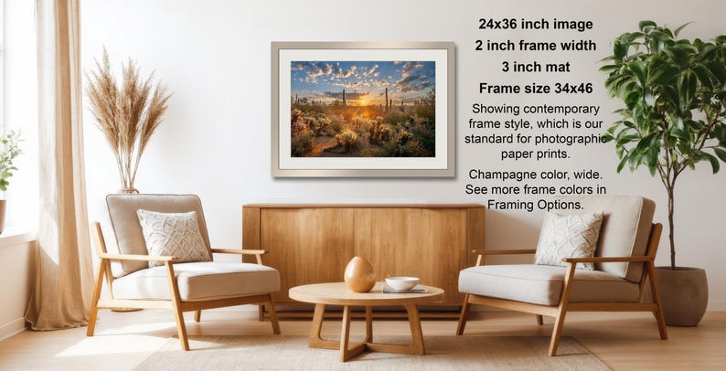 a living room with a wooden coffee table, two white armchairs, and a framed landscape photograph hanging on the wall.