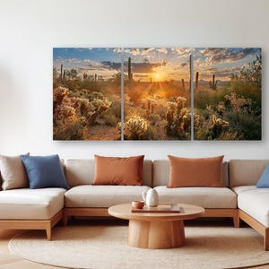 a living room with a large, colorful painting of a desert landscape hanging on the wall. The painting depicts a desert scene with cacti, shrubs, and a sunset. The room has a beige sofa and a wooden coffee table, and there are several potted plants placed around the space.