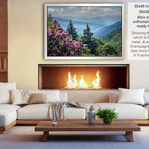 a cozy living room with a fireplace, white sofas, and a coffee table. The room has a warm and inviting atmosphere, with a fireplace providing a focal point and a painting of a mountain landscape hanging above it.