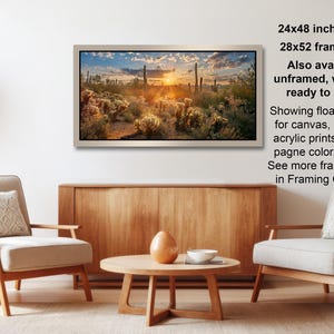 a living room with a wooden coffee table, two white armchairs, and a framed landscape painting hanging on the wall.