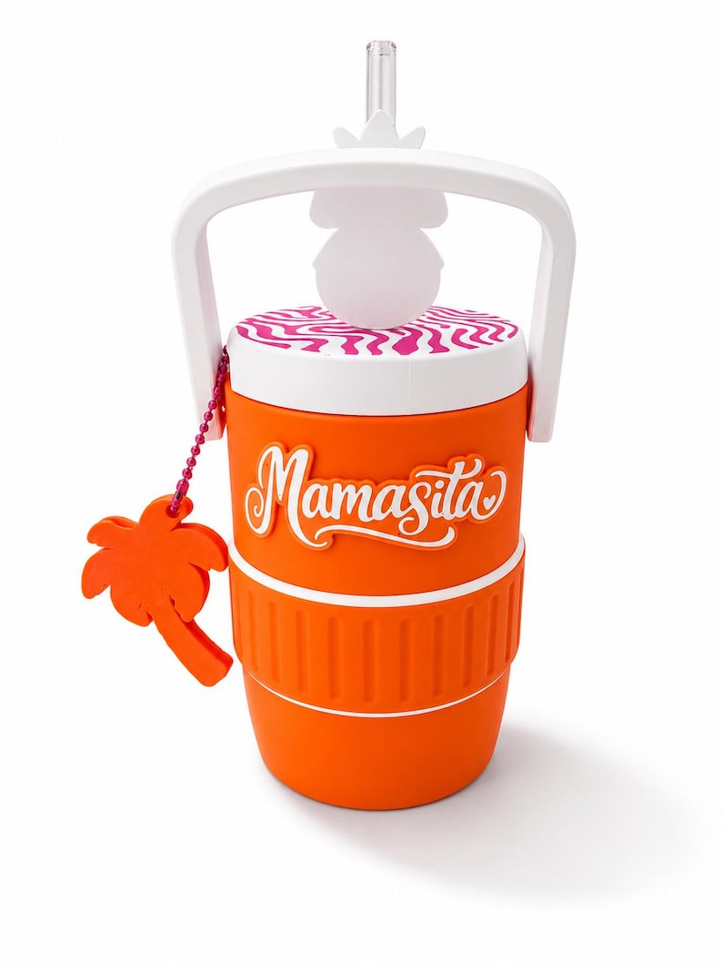 May include: An orange tumbler with a white handle and a clear straw. The lid features a pink and white wavy pattern. The word "Mamasita" is written in white script on the front. An orange palm tree charm hangs from a pink beaded chain.