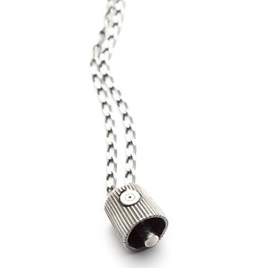 May include: A silver chain necklace with a silver pendant shaped like a spray paint can lid.