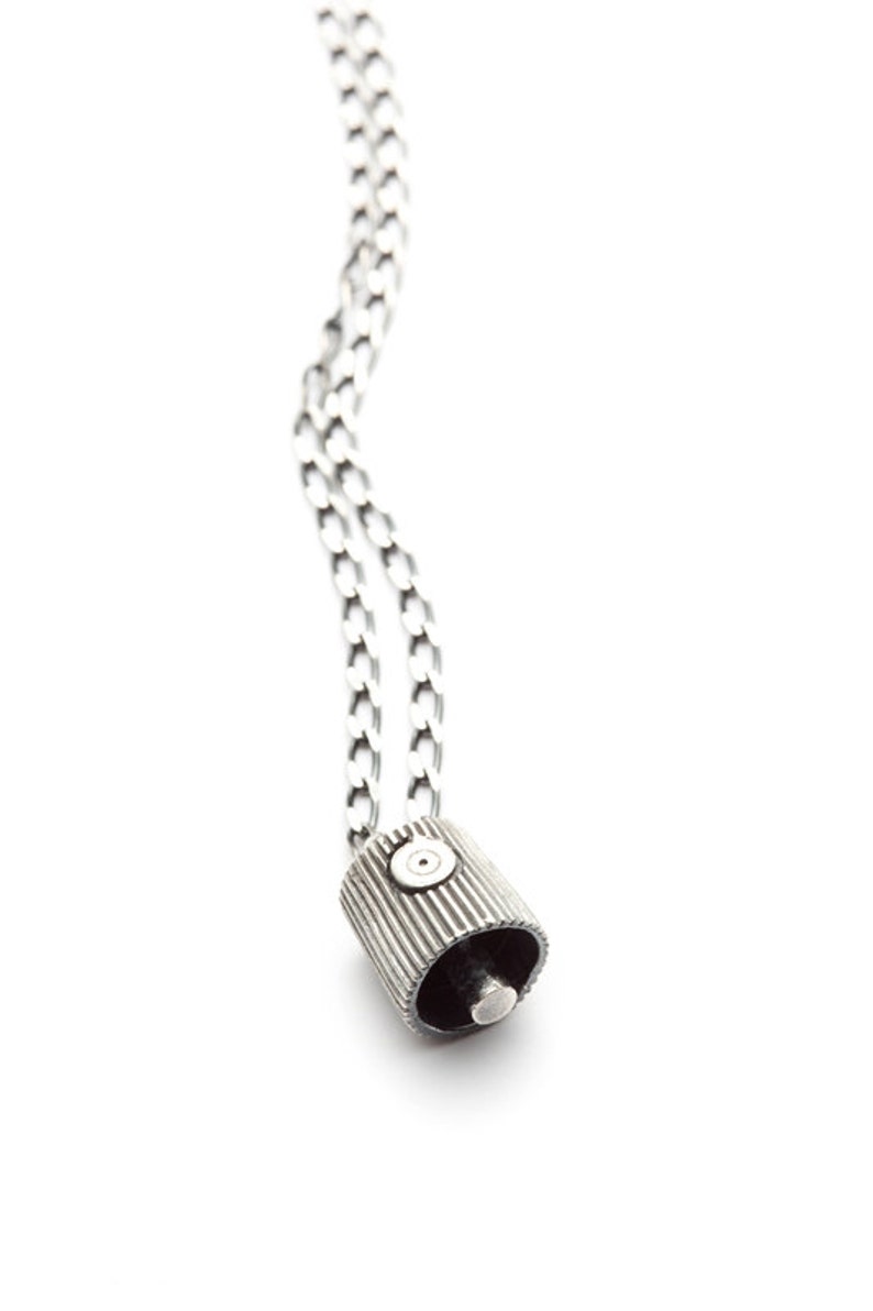 May include: A silver chain necklace with a silver pendant shaped like a spray paint can lid.