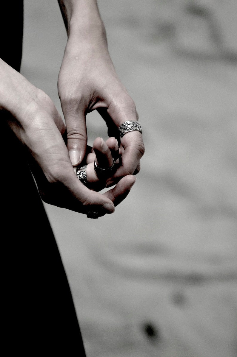 May include: Close-up of a person's hands wearing several silver rings with intricate designs.