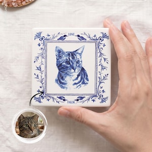 Może przedstawiać: Kwadratowa biała płytka ceramiczna z niebieską ilustracją przedstawiającą kota pręgowanego w centrum. Kot jest otoczony ozdobną ramką z niebieskich pnączy, liści i małych ptaków. Słowo LOVE jest nadrukowane na górze, a TIGER na dole.