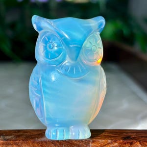 Könnte beinhalten: Eine kleine, blaue Opal-Eulenfigur. Die Eule hat detaillierte Schnitzereien und schimmernde Farben.