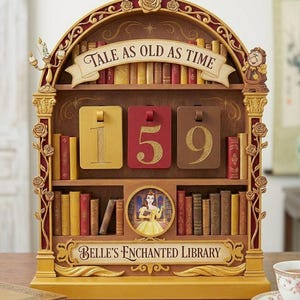 Op de afbeelding: Een decoratief rek met de tekst "TALE AS OLD AS TIME" en "BELLE'S ENCHANTED LIBRARY". Het rek toont een miniatuur bibliotheek met boeken, een afbeelding van Belle en nummerblokken met "159". Het kleurenschema omvat goud, rood en bruin.