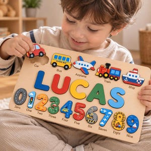 May include: A wooden puzzle board featuring the name LUCAS in large, colorful letters, surrounded by cutouts for a car, bus, airplane, train, and ship. Below, the numbers zero through nine are displayed with corresponding labels and illustrations.