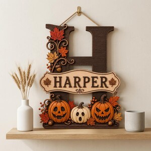 May include: A dark brown wooden letter H wall sign featuring the name HARPER on a light wood plaque. The sign is decorated with orange and red maple leaves, acorns, and three carved pumpkins with different facial expressions on the base.