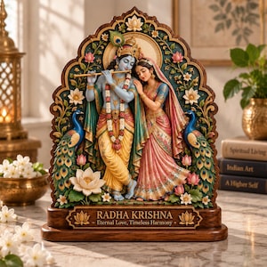 May include: A decorative sculpture of Radha and Krishna standing together, featuring Krishna playing a flute and Radha leaning on his shoulder. The piece is framed by peacocks and lotus flowers, with a base inscribed with RADHA KRISHNA Eternal Love, Timeless Harmony.