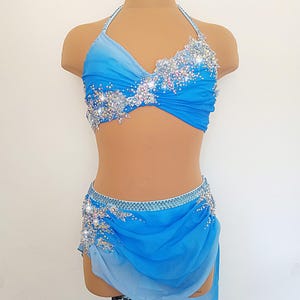 May include: A blue and white dance costume with a halter top and a skirt. The top and skirt are decorated with rhinestones and sequins.