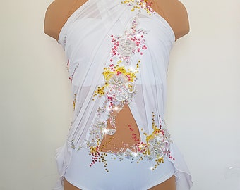 May include: White dance costume with a halter neckline and a sheer overlay. The costume is embellished with white, pink, and yellow rhinestones and sequins in a floral design. The costume has a white, ruffled skirt.
