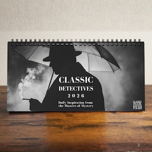 Puede incluir: Un calendario de escritorio en blanco y negro para 2026. Presenta la silueta de un detective bajo un paraguas, fumando un cigarrillo. El calendario se titula "CLASSIC DETECTIVES" con el texto "Daily Inspiration from the Masters of Mystery."
