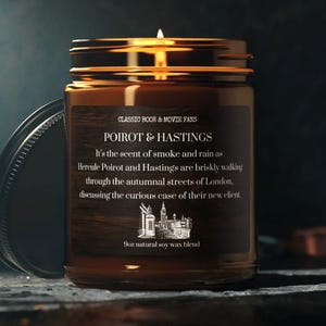 Könnte beinhalten: Ein braunes Glas-Kerzengefäß mit einem goldenen Deckel. Das Etikett lautet "CLASSIC BOOK & MOVIE FANS POIROT & HASTINGS It's the scent of smoke and rain as Hercule Poirot and Hastings are briskly walking through the autumnal streets of London, discussing the curious case of their new client. 100% natural soy wax blend."