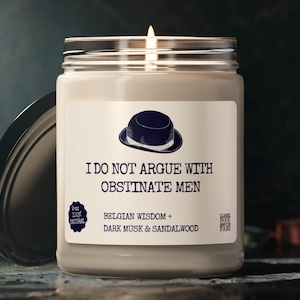 Könnte beinhalten: Eine brennende, cremefarbene Kerze in einem Glas mit silbernem Deckel. Auf dem Etikett steht "I DO NOT ARGUE WITH OBSTINATE MEN" mit einer Bowlerhut-Illustration. Die Kerze ist 227g und hat einen Duft von Belgian Wisdom, Dark Musk & Sandalwood.