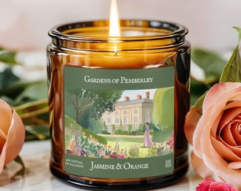 May include: A lit, amber-colored glass candle jar with a label that reads "Gardens of Pemberley" and "Jasmine & Orange." The label features a watercolor illustration of a garden and a stately home. The candle is surrounded by pink roses.
