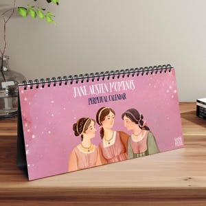 May include: A pink perpetual calendar with a black spiral binding. The calendar features an illustration of three women with long brown hair, wearing dresses and necklaces. The text "Jane Austen Moments" and "Perpetual Calendar" is printed on the front of the calendar.