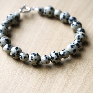 May include: A bracelet made of white and black speckled beads with a silver clasp.