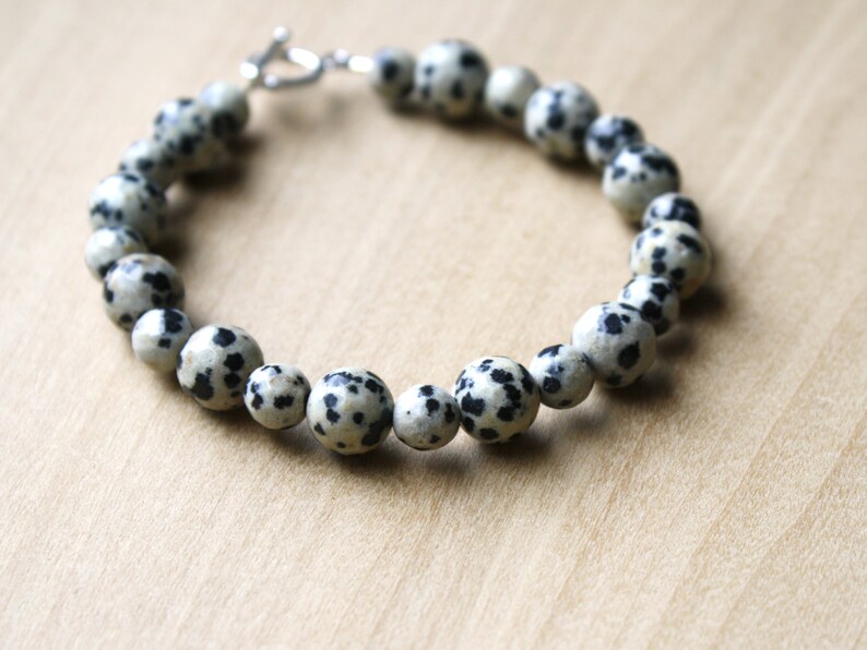 May include: A bracelet made of white and black speckled beads with a silver clasp.