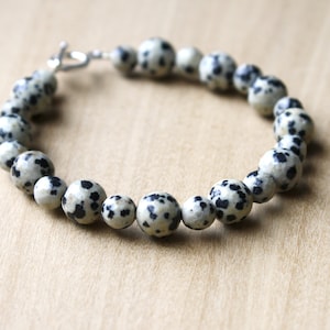 May include: A bracelet made of black and white dalmatian jasper beads with a silver clasp.