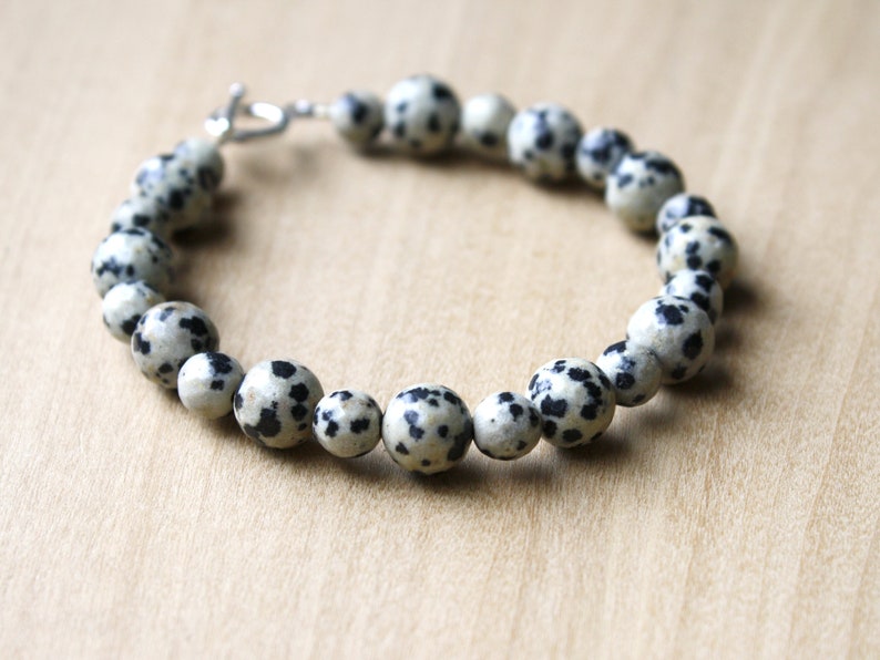 May include: A bracelet made of black and white dalmatian jasper beads with a silver clasp.