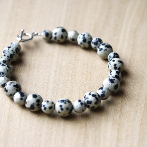 May include: A bracelet made of white and black dalmatian jasper beads with a silver clasp.