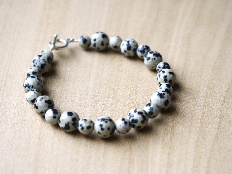 May include: A bracelet made of white and black dalmatian jasper beads with a silver clasp.