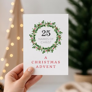 May include: A white Christmas Advent card held by a hand. The card features a green wreath with red berries around the number 25 and the text "NAMES OF CHRIST". Below the wreath, the card reads "A CHRISTMAS ADVENT" in red.