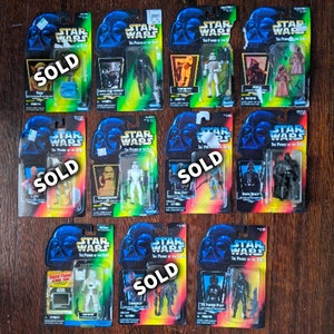 May include: A collection of 12 Star Wars action figures in their original packaging. The figures are from the "The Power of the Force" series and feature characters like Yoda, Darth Vader, and Boba Fett. The packaging is mostly black and blue with the Star Wars logo and the words "The Power of the Force" printed on it. The figures are all sold.