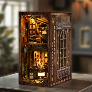 May include: A miniature wooden Serenity Coffee House model with intricate details. The model features a coffee shop interior with a counter, tables, and shelves filled with items. The exterior has a window and the words "SERENITY COFFEE HOUSE" vertically on the side.