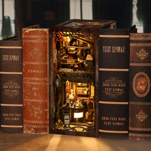 May include: A detailed miniature wooden diorama of a bookshelf interior, lit with warm lighting. The diorama is framed by several decorative books with embossed text and ornate covers, creating a cosy, inviting atmosphere.