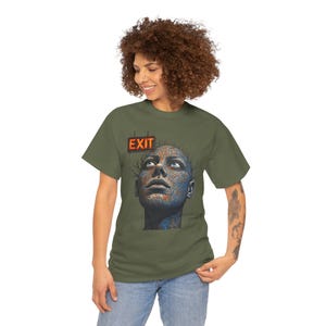 May include: Olive green t-shirt featuring a graphic of a human face with a circuit board design and blue eyes, looking upwards. The word "EXIT" is displayed above the graphic in a red and orange sign.