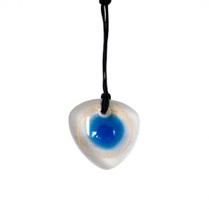 May include: A pendant necklace with a clear, teardrop-shaped glass pendant. It has a bright blue centre and a gold-coloured ring. The pendant hangs from a black cord.
