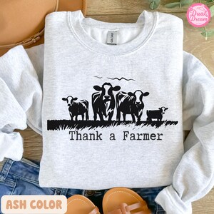 May include: A grey sweatshirt with a black silhouette of cows and the text "Thank a Farmer".