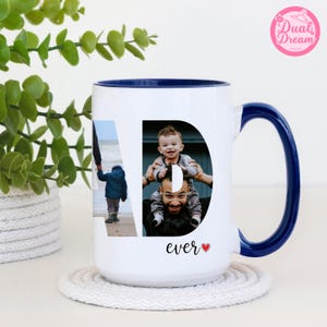 May include: White ceramic mug with a blue interior and handle. The mug features a photo collage in the shape of the letter "D" with the word "ever" and a heart symbol. The mug is on a white coaster with a green plant in the background.