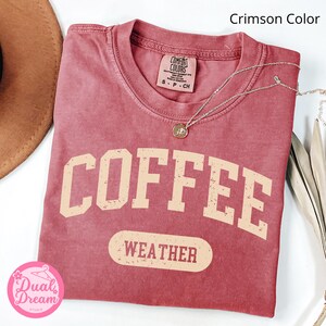 K&ouml;nnte beinhalten: T-Shirt in einem kr&auml;ftigen Rot mit einem verwaschenen Vintage-Motiv, das "COFFEE WEATHER" in hellem Beige zeigt.