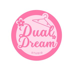 May include: Pink circle logo with the text "Dual Dream Studio" in a white cursive font. A white hanger with a hook is above the text. A small white flower is to the left of the text and another small white flower is to the right of the text.