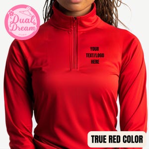 May include: Red long-sleeve mock neck shirt with a zipper. The shirt has the text "YOUR TEXT/LOGO HERE" printed on the front.